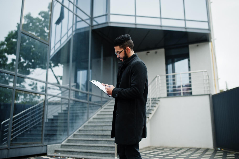 Sicherheitsmitarbeiter erstellt ein Kontrollprotokoll vor einem modernen Gebäude, vorbereitet für Objektschutz und Zutrittskontrolle